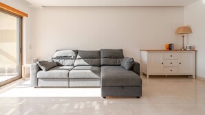 Ein modernes Wohnzimmer mit einem grauen Ecksofa, einer weißen Kommode und einer Stehlampe.