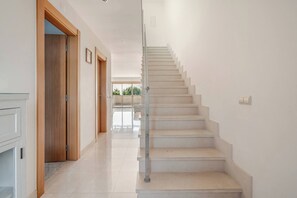 A modern interior with a staircase leading to an upper floor, a hallway with wooden doors, and a view of the outdoors. - Charming Holiday House With Stunning Views in Albufeira (Albufeira)