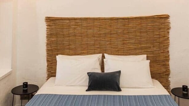 A bed with a woven headboard, white pillows, and a blue striped bedspread. There are two bedside tables with lamps. - Villa LuxL Family House (Mesaria)