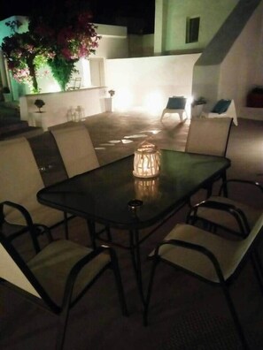 An outdoor patio with a table and chairs, a lamp, and a staircase leading to an upper level. - Villa LuxL Family House (Mesaria)