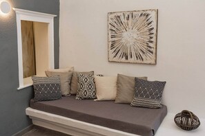 A sofa with patterned cushions, a wall-mounted abstract artwork, and a small decorative item on the floor. - Villa LuxL Family House (Mesaria)
