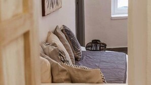 A bedroom with a bed, pillows, a wall-mounted artwork, a window, and a door. - Villa LuxL Family House (Mesaria)