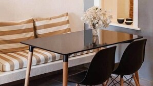 A modern dining area with a glass table, black chairs, and a striped sofa. - Villa LuxL Family House (Mesaria)