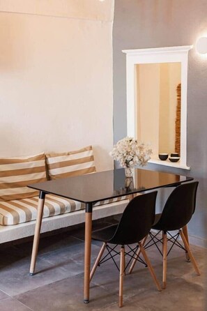 A modern dining area with a glass table, black chairs, and a striped sofa. - Villa LuxL Family House (Mesaria)