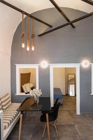 A modern interior with a sofa, dining table, and chairs, a hanging light fixture, and two illuminated wall sconces. - Villa LuxL Family House (Mesaria)