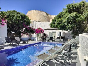 En swimmingpool med solstolar och utsikt över en kulle.