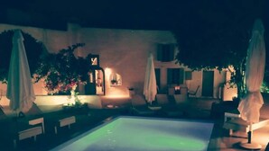 A nighttime swimming pool area with lounge chairs and umbrellas. - Villa LuxL Family House (Mesaria)