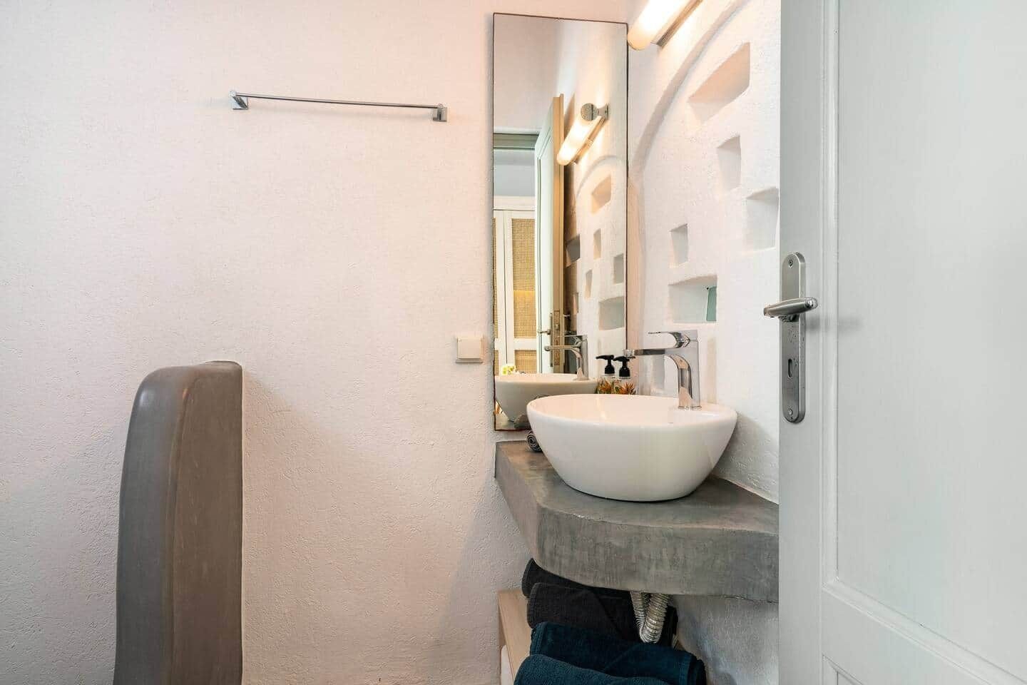 Ein Badezimmer mit einem weißen Waschbecken, einem Spiegel und einem Handtuchhalter.
