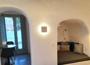A room with a dining table and chairs, a sofa with cushions, and a wall-mounted light fixture. - Villa LuxL Distillery Studio (Mesaria)