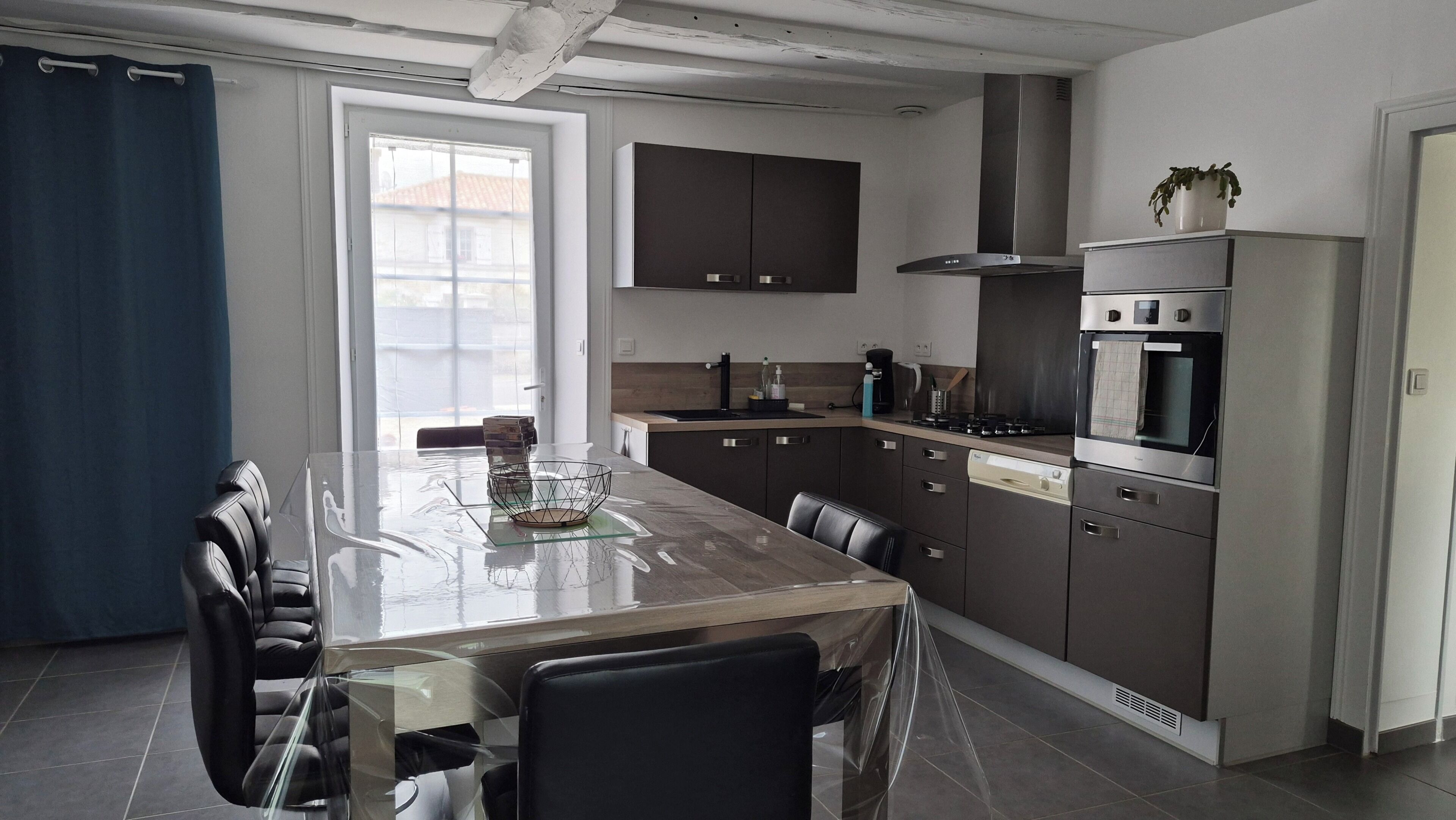 A modern kitchen with dark cabinetry, a stainless steel range hood, and a built-in oven.