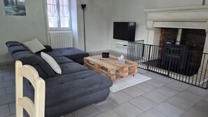 A modern living room with a grey sectional sofa, a wooden coffee table, a flat-screen TV, and a fireplace. - Maison élégante et calme (VOUZAN)