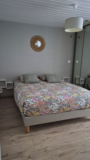 Une chambre à coucher avec un lit, un miroir rond et un luminaire suspendu.