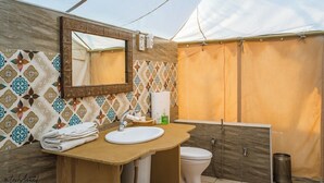 A bathroom with a wooden vanity, a sink, a mirror, a toilet, and a shower curtain.
