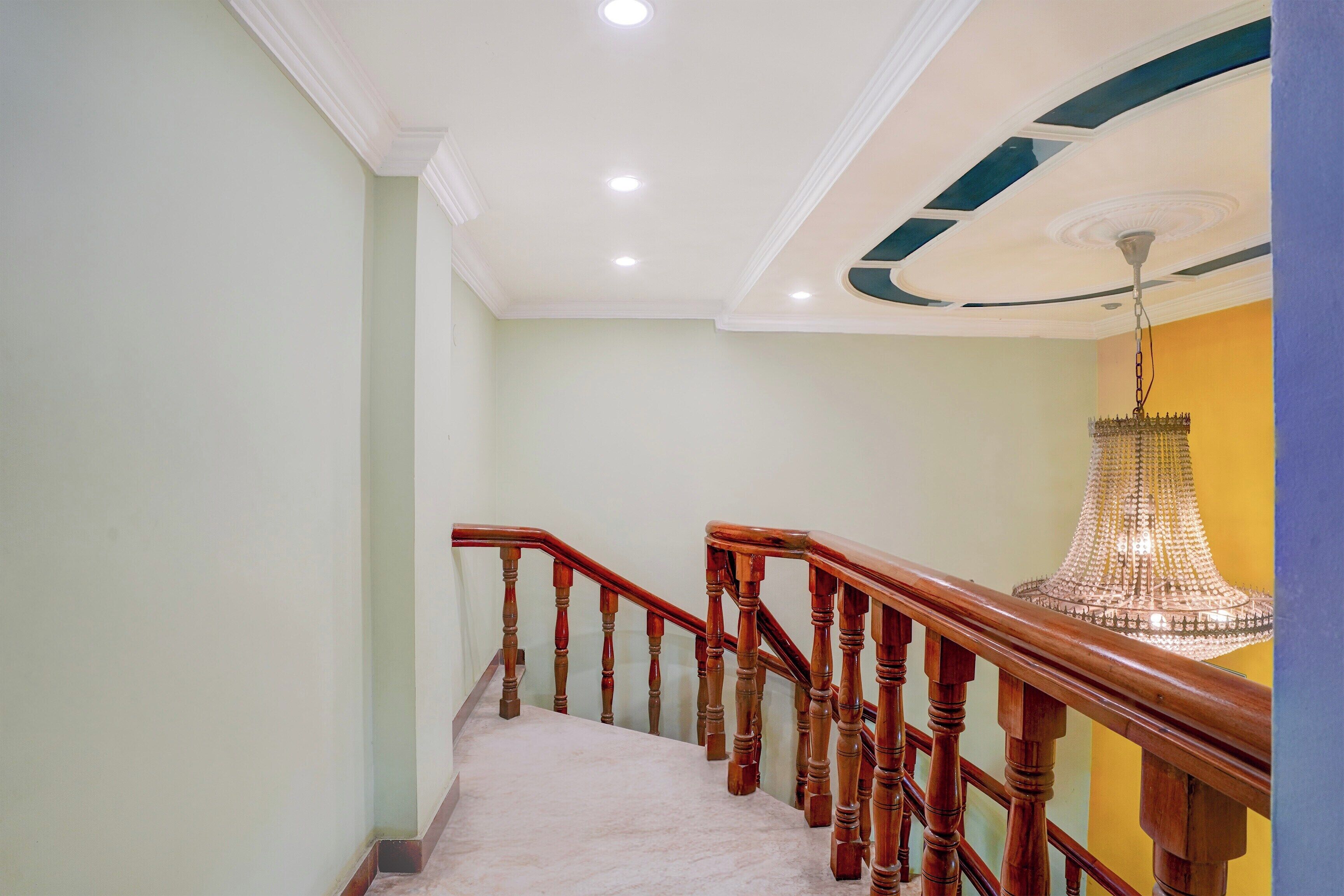 A staircase with wooden handrails and a marble floor, leading to a room with a chandelier.