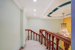A staircase with wooden handrails and a marble floor, leading to a room with a chandelier. - CollectionO Sri Varadaraja PerumalTemple (Puducherry)