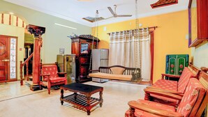 Ein stilvolles Wohnzimmer mit Sofa, Sesseln, Couchtisch, Deckenventilator und einem dekorativen Schrank.