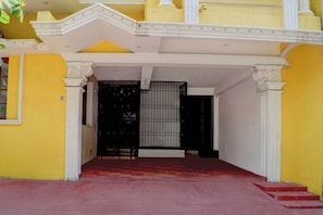 A building entrance with a gated door, a staircase, and a red carpet leading to a landing. - CollectionO Sri Varadaraja PerumalTemple (Puducherry)