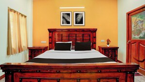 Ein Hotelzimmer mit einem großen hölzernen Bett, zwei Nachttischen, einer Wandleuchte und zwei gerahmten Kunstwerken.