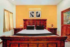 Una habitación de hotel con una cama de madera grande, dos mesitas de noche, una lámpara de pared y dos cuadros enmarcados.