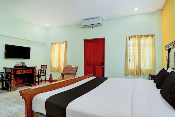 A hotel room with a bed, a desk, a chair, a television, and a red door. - CollectionO Sri Varadaraja PerumalTemple (Puducherry)