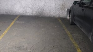 A parking garage with concrete walls and a car parked in a space marked with yellow lines. - Central Seville Apartment with Terrace, Balconies, and Prime Location (Seville)