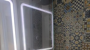 A bathroom with a white sink, a glass-enclosed shower, and a tiled wall with a geometric pattern. - Central Seville Apartment with Terrace, Balconies, and Prime Location (Seville)
