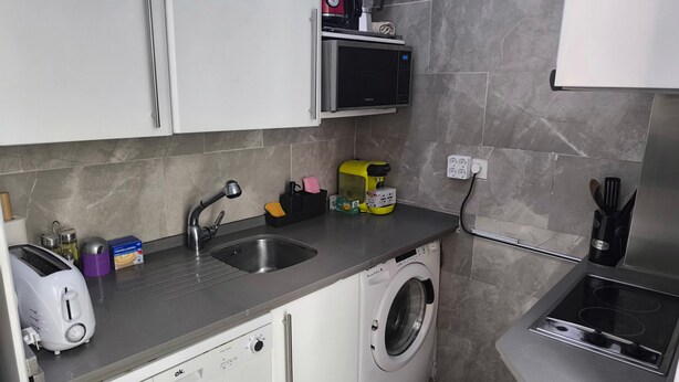 A compact kitchen with a washing machine, a microwave, and a toaster. - Central Seville Apartment with Terrace, Balconies, and Prime Location (Seville)