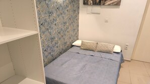 A bedroom with a bed, a wardrobe, and a floral wallpaper. - Central Seville Apartment with Terrace, Balconies, and Prime Location (Seville)