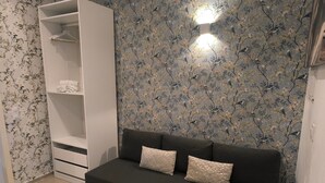 A room with a dark sofa, patterned wallpaper, and a white wardrobe. - Central Seville Apartment with Terrace, Balconies, and Prime Location (Seville)