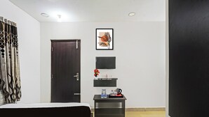 A hotel room with a bed, a small table with a kettle, a framed picture, and a door. - Collection O Vanamthopu Center Nellore (Nellore)