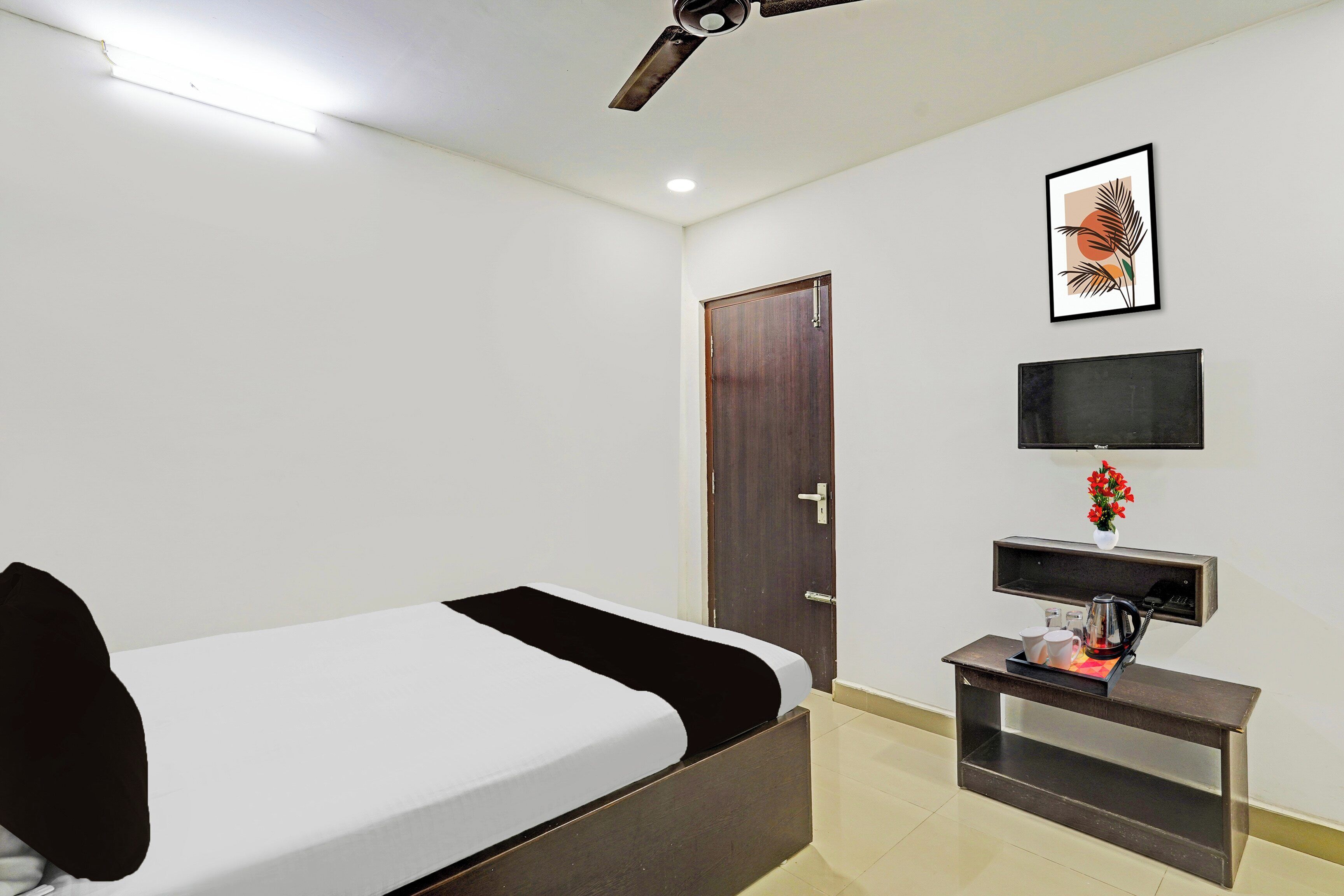 A hotel room with a bed, a desk with a telephone, a television, and a door.