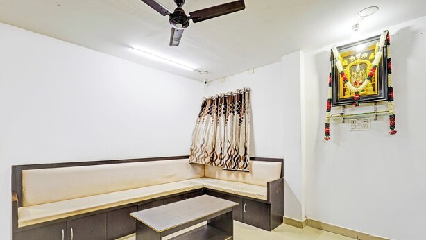 A room with a sofa, a ceiling fan, and a wall-mounted decoration. - Collection O Vanamthopu Center Nellore (Nellore)