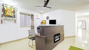 A reception area with a reception desk, a clock, a television, and a ceiling fan. - Collection O Vanamthopu Center Nellore (Nellore)
