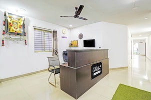 Un espace d’accueil comprenant un comptoir de réception, une horloge, un téléviseur et un ventilateur de plafond.