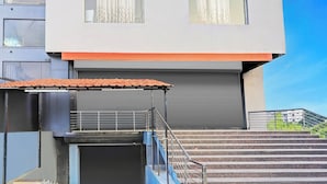 A modern building with a flat roof, a set of stairs leading to a garage door, and a metal railing. - Collection O Vanamthopu Center Nellore (Nellore)