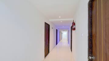 A corridor with doors on both sides, a fire extinguisher mounted on the wall, and a light fixture on the ceiling.