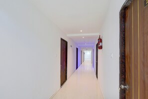 A corridor with doors on both sides, a fire extinguisher mounted on the wall, and a light fixture on the ceiling. - Super Collection O Pragathi Nagar (Nizamabad)