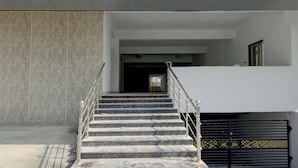 Una escalera conduce a un nivel superior, con barandilla de metal y un portón negro al final.