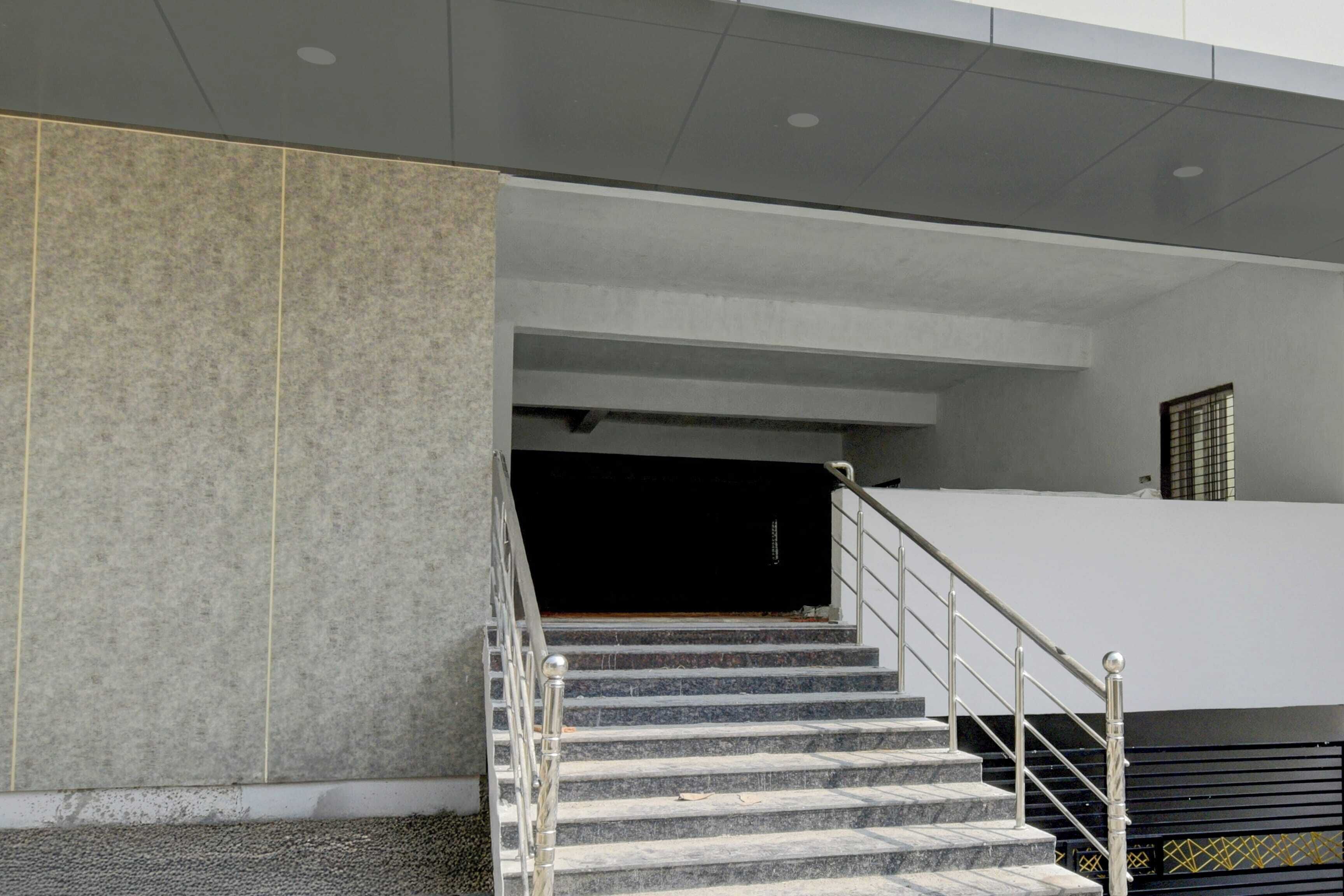 A staircase leading to an upper level with a metal handrail and a dark-colored wall at the top.