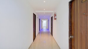 Un pasillo de hotel con puertas de madera, un extintor de incendios en la pared y un cartel de número en una puerta.
