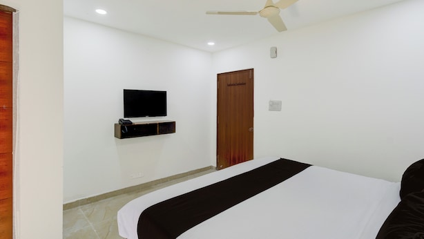 Un dormitorio con cama, ventilador de techo, televisor montado y puerta de madera.