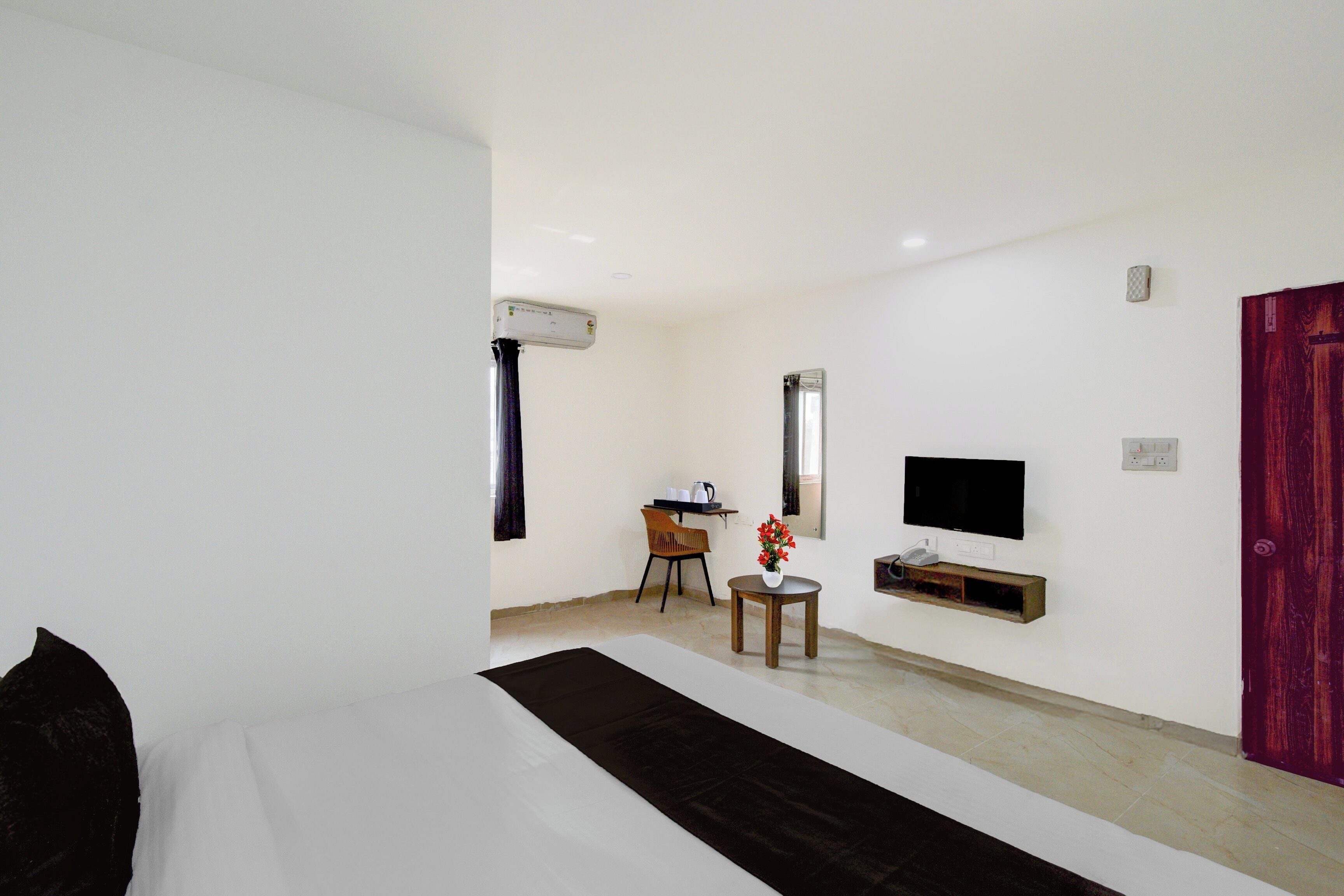 Une chambre d’hôtel avec un lit, un bureau, une chaise, une télévision et une porte.