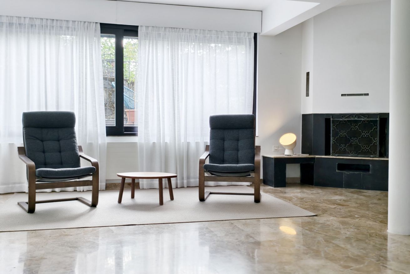 Un salon moderne avec deux fauteuils, une petite table et une cheminée.