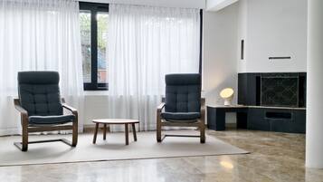 Un salon moderne avec deux fauteuils, une petite table et une cheminée.