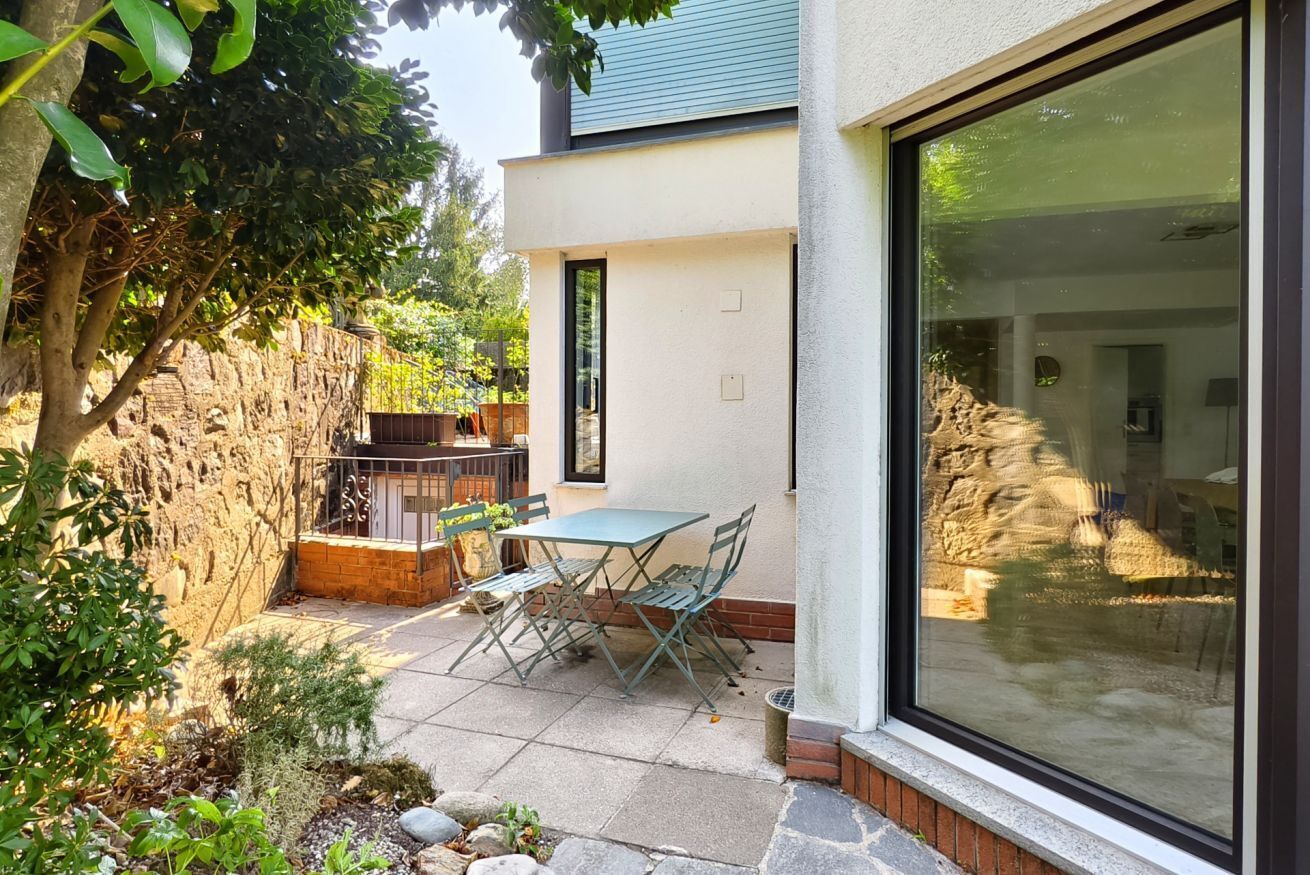 A patio with a table and chairs, a stone wall, and a large sliding glass door.