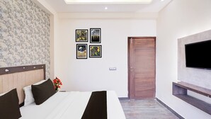 Una habitación de hotel con una cama, un televisor instalado en la pared y cuadros enmarcados.