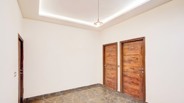 Un pasillo con tragaluz, dos puertas de madera y un suelo de mármol.