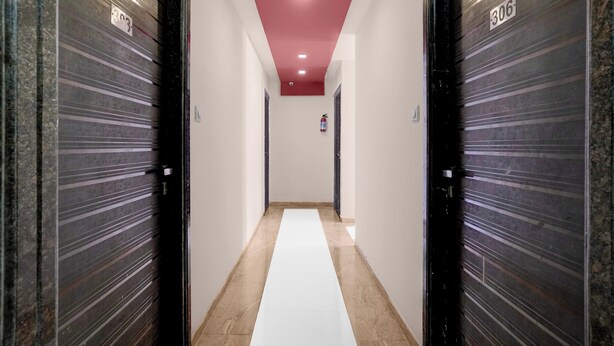A hallway with closed doors, a fire extinguisher, and a red ceiling light. - Collection O Asalpha Metro Station (Mumbai)