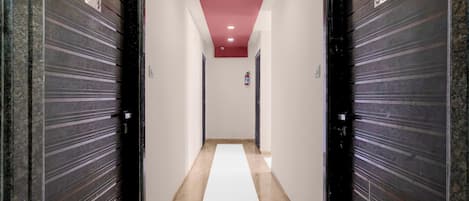 A hallway with closed doors, a fire extinguisher, and a red ceiling light.