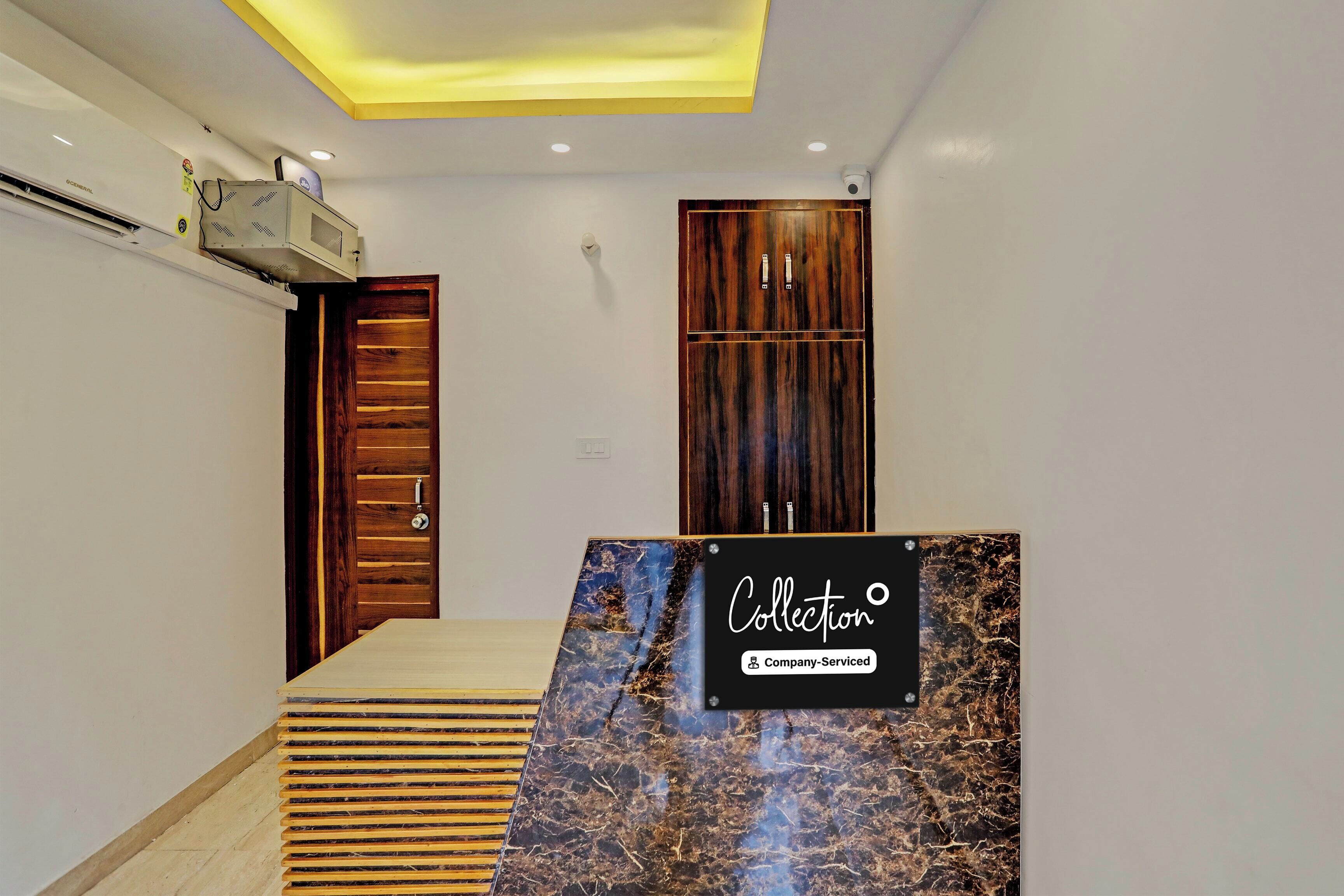 A hotel reception area with a marble counter, wooden doors, and a ceiling with recessed lighting.